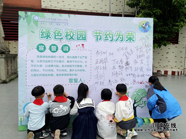 胡市镇中心校学生们在“绿色校园 节约为荣”签名墙上写下自己的名字.jpg