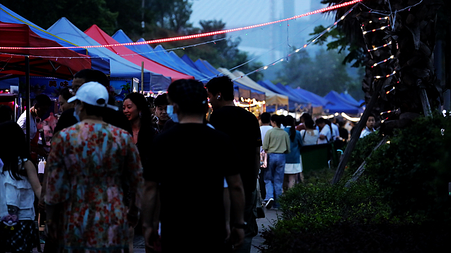 nEO_IMG_走进泸州市龙马潭区安宁街道北滨路夜市，人声鼎沸，摊位上暖暖的灯光映照着滚滚沱江水，200余家摊位鳞次栉比、生意兴旺，市井气息扑面而来，来来往往的市民穿梭在街头，尽情品尝美食、打卡游玩。+(3) (1).jpg