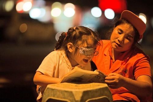 路灯下的母爱：宜宾环卫工边扫地边辅导女儿(图2)