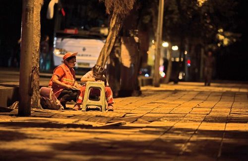 路灯下的母爱：宜宾环卫工边扫地边辅导女儿(图1)