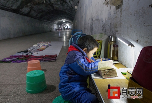 自贡：妈妈洞子里摆地摊&nbsp;儿子在旁边写作业(图1)