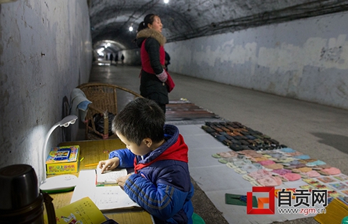 自贡：妈妈洞子里摆地摊&nbsp;儿子在旁边写作业(图2)
